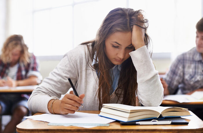 Young woman looking frustrated and stressed while studying, illustrating the bitter aftertaste of revenge stories.