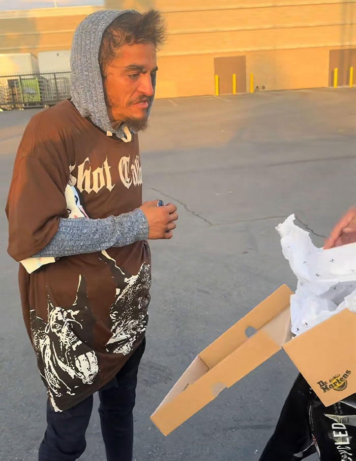 Nickelodeon star wearing a hoodie and graphic shirt receiving shoes from a box, highlighting struggle with homelessness outdoors. Nickelodeon star wearing a hoodie and graphic shirt receiving shoes from a box, highlighting struggle with homelessness outdoors.
