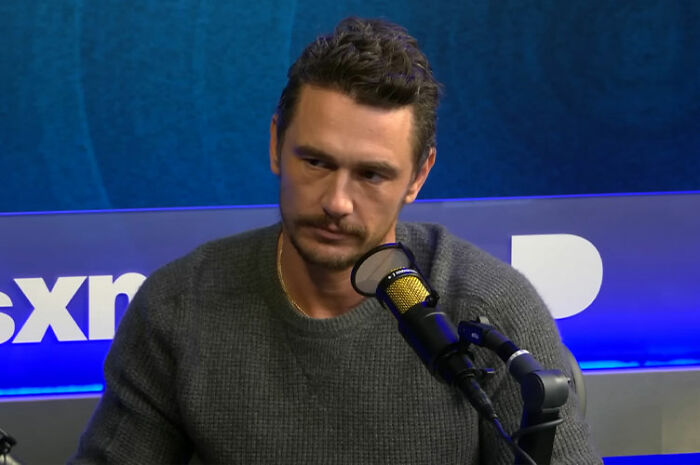 James Franco speaking into a microphone during a podcast interview, sharing insights about being cast out of Hollywood.