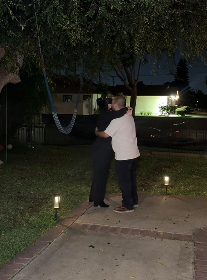 Couple hugging outside at night after heartfelt proposal, people are freaking out over woman's romantic gesture. Couple hugging outside at night after heartfelt proposal, people are freaking out over woman's romantic gesture.