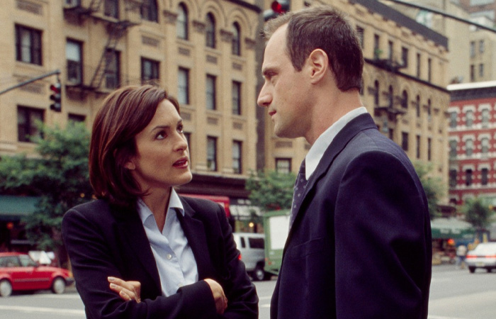 Two actors in suits having a serious conversation on a city street, representing longest running TV shows.