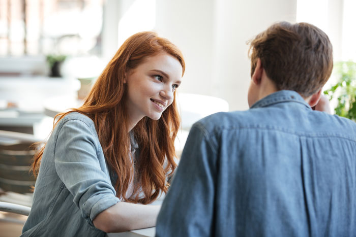 A young woman and man in denim shirts having a candid conversation about things women do to seem attractive.
