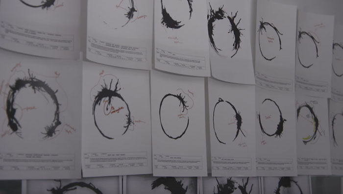 Abstract black circle drawings pinned on a wall, representing experiences of people who couldn’t sleep after spending time in the woods.