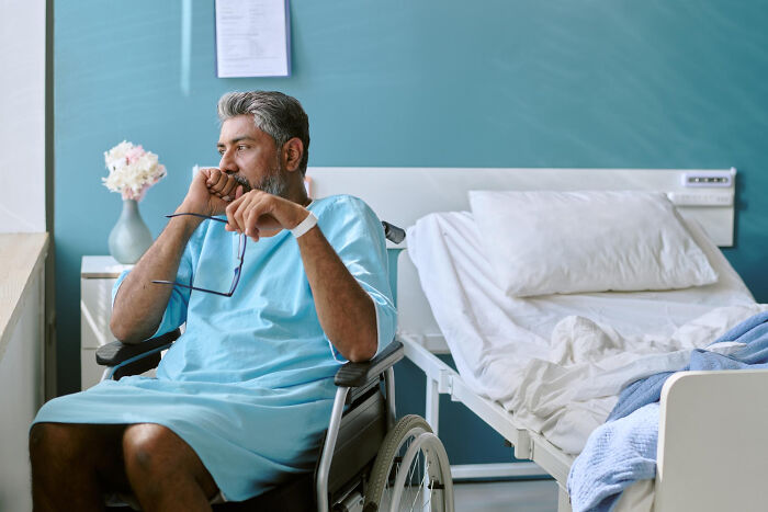 Middle-aged man in hospital gown sitting in wheelchair in a medical room, reflecting on disturbing science facts.