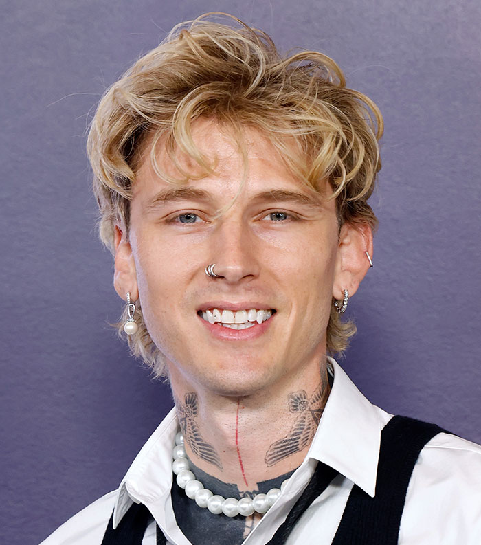 Young male celebrity with blonde hair, piercings, and tattoos smiling for the most disliked celebrities of 2025.