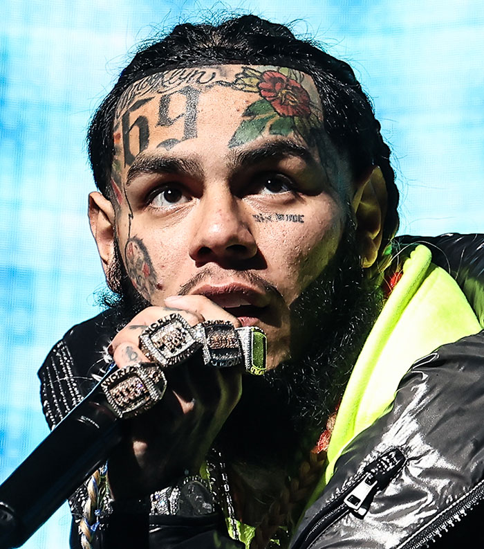 Close-up of a tattooed male celebrity performing on stage, representing the most disliked celebrities of 2025.