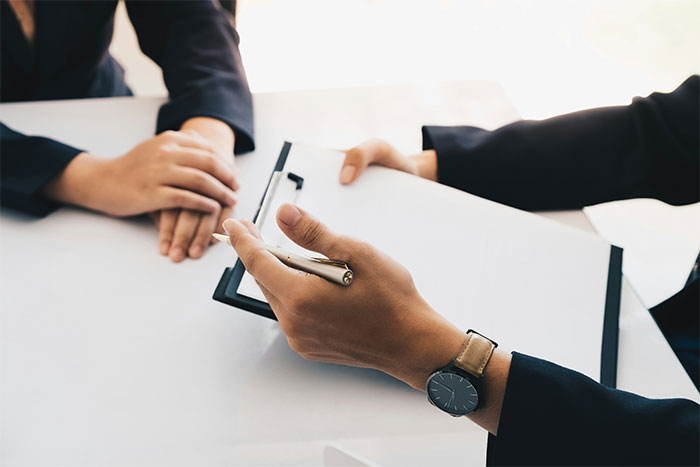 Two employees in a discussion, one pushing back against vegan-only club with a clipboard and pen in hand. Two employees in a discussion, one pushing back against vegan-only club with a clipboard and pen in hand.