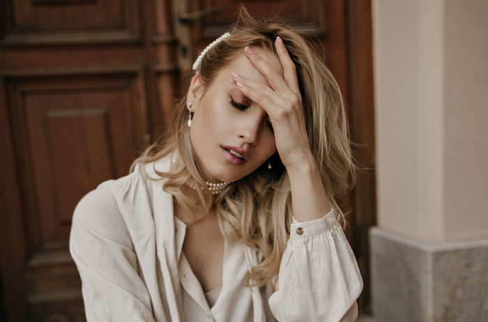 Woman covering her face with hand, looking stressed, representing husband and family call about picky eater allergies. Woman covering her face with hand, looking stressed, representing husband and family call about picky eater allergies.