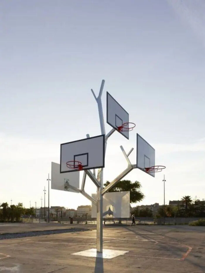 Trippy basketball hoop installation with multiple backboards and rims resembling a tree in an outdoor court setting.
