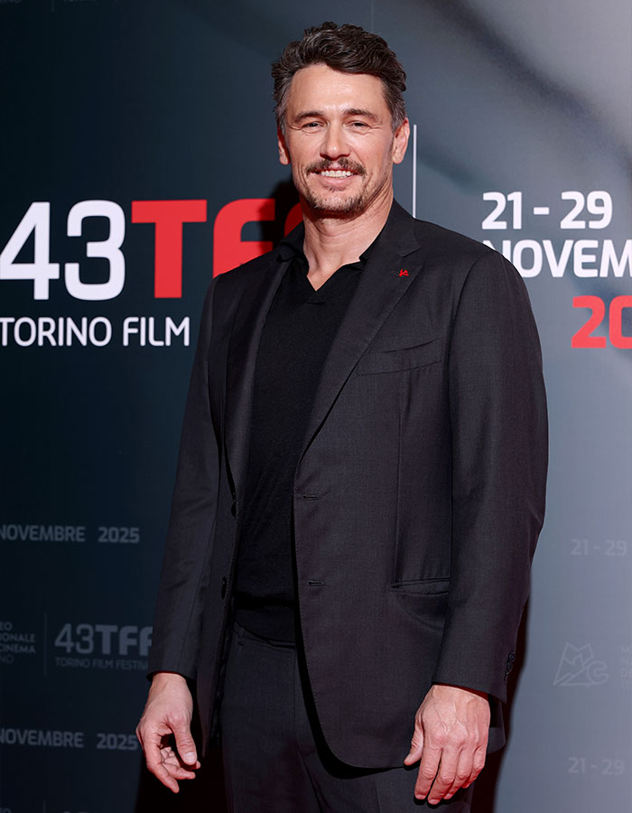James Franco smiling at a film festival event, dressed in a black suit, reflecting on Hollywood experiences.