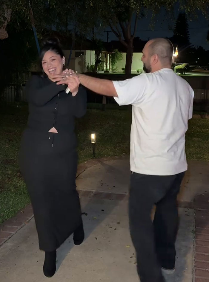 Woman and man dancing outdoors at night, capturing a moment after a proposal that people are freaking out about. Woman and man dancing outdoors at night, capturing a moment after a proposal that people are freaking out about.