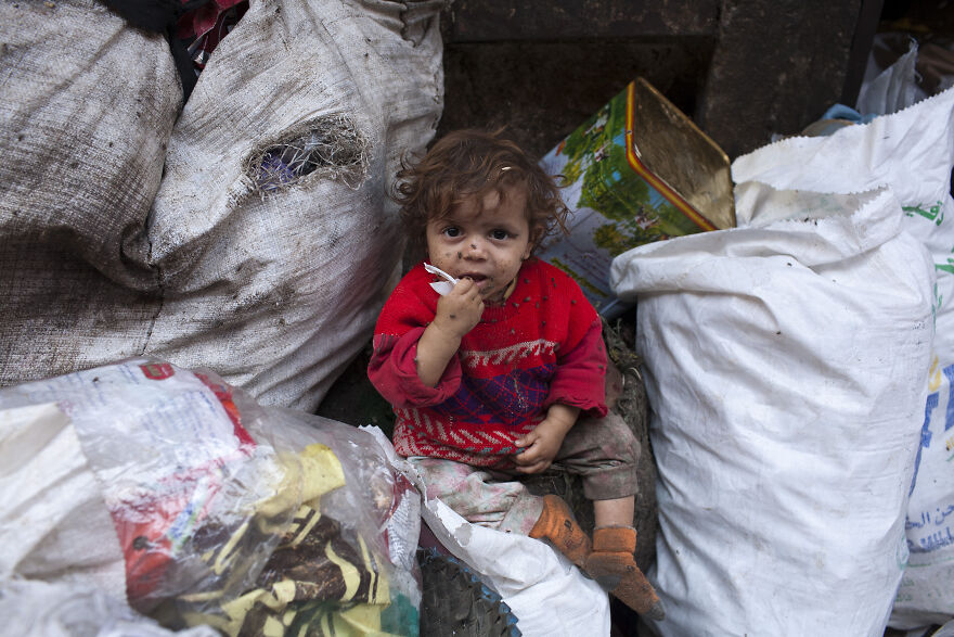 A young child sitting amid large trash bags and debris, highlighting pollution in the dirtiest countries in the world. A young child sitting amid large trash bags and debris, highlighting pollution in the dirtiest countries in the world.