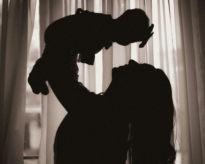 Silhouette of a parent lifting their child, capturing a tender moment between little kids and parents.