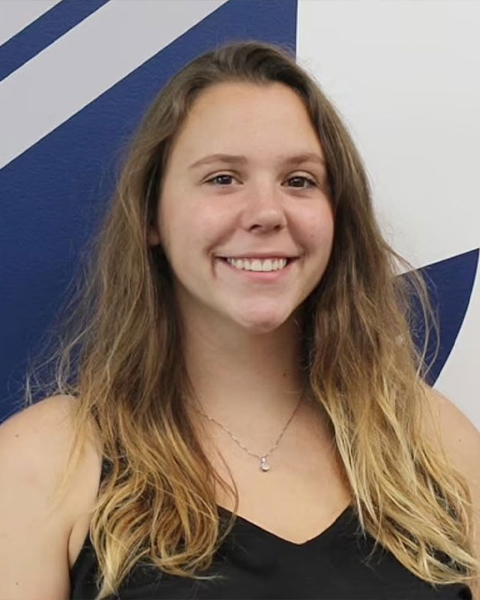 Young woman with long hair smiling in front of a blue and white background, related to engaged teacher text messages case