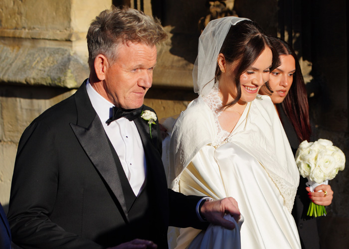Gordon Ramsay with his daughter wearing a satin bed sheet wedding dress, smiling and walking outdoors in sunlight. Gordon Ramsay with his daughter wearing a satin bed sheet wedding dress, smiling and walking outdoors in sunlight.