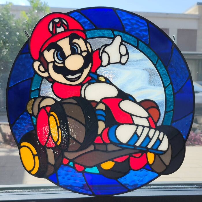 Stained glass artwork of a pop culture icon Mario driving a kart, showcasing vivid colors and intricate design details.