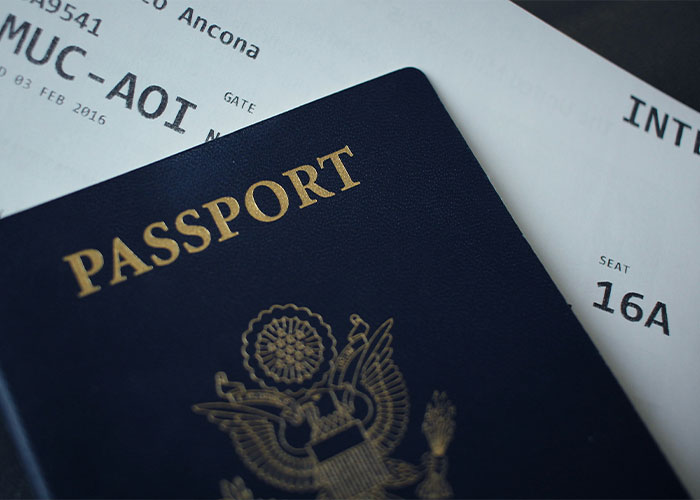Close-up of a passport and flight boarding pass highlighting seating assigned on an airplane during travel dispute.