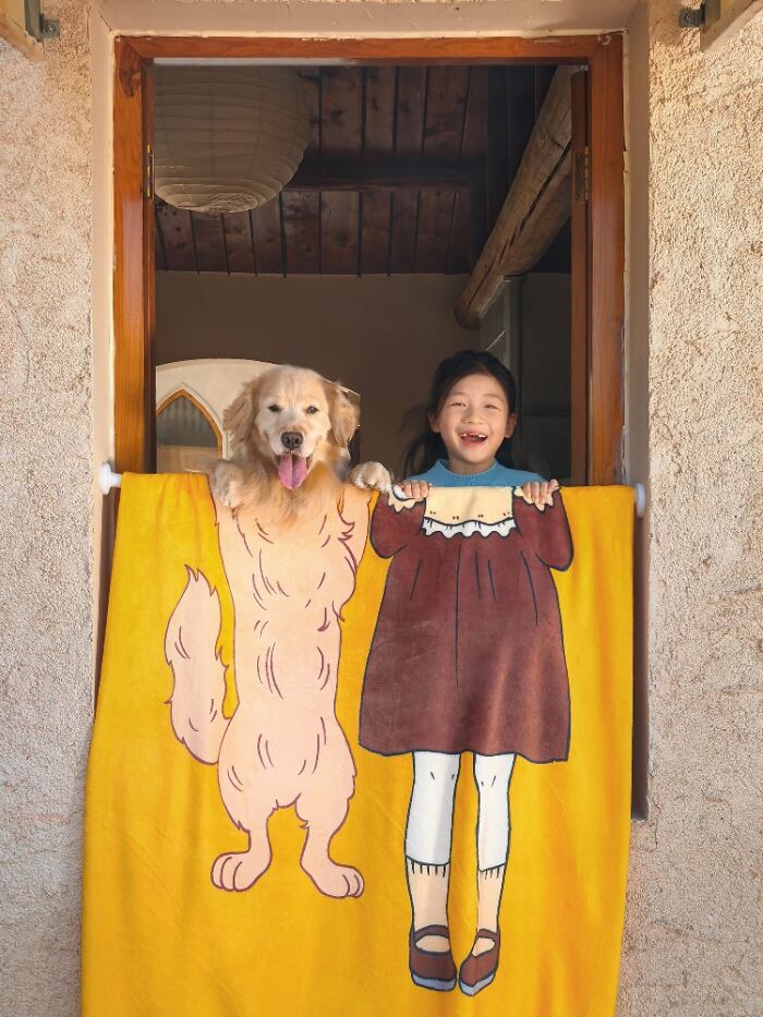Golden retriever and smiling child behind a colorful blanket, a creative example of the best dog photos in the world.