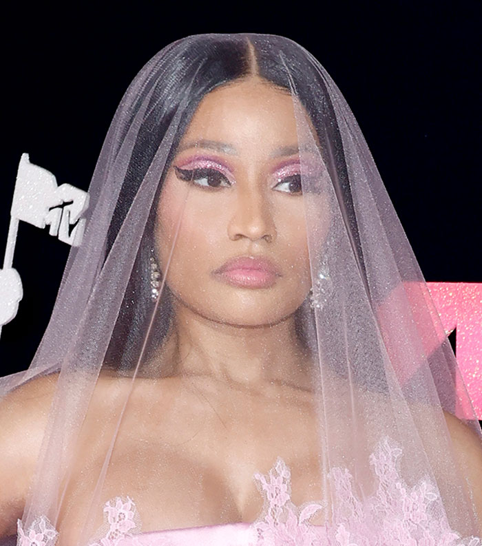 Celebrity with pink makeup and veil at an event representing most disliked celebrities of 2025.