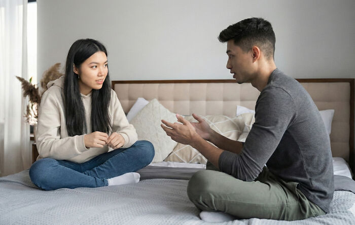 Two people sitting on a bed, engaged in a lively conversation, enjoying the best party game experience.
