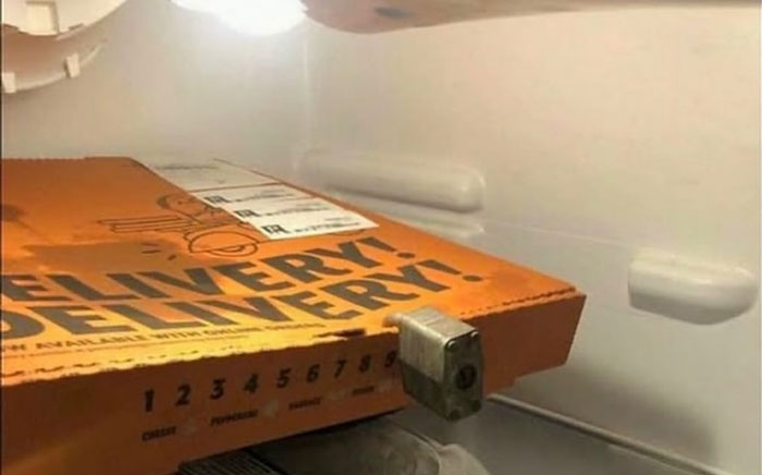 Pizza box secured inside fridge door with a lock, showcasing a creative example of dude fridges.
