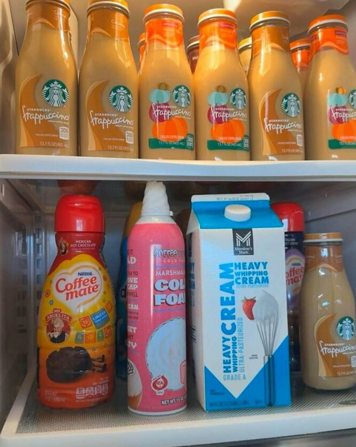 Open fridge shelves stocked with Starbucks Frappuccino bottles, coffee creamer, whipped cream, and heavy whipping cream carton.