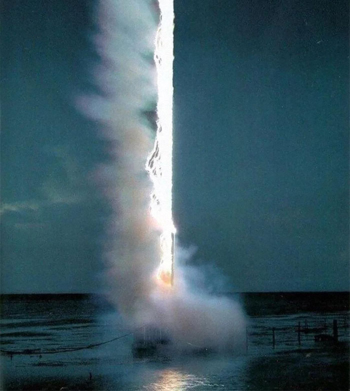 Rocket launch with bright light and smoke over water, symbolizing exploration of existence reality and the universe concepts.