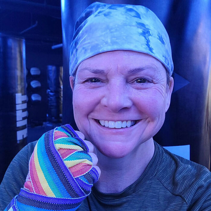 Smiling woman wearing a headscarf and rainbow hand wrap at a boxing gym, related to Marvelous Mrs. Maisel actress news. Smiling woman wearing a headscarf and rainbow hand wrap at a boxing gym, related to Marvelous Mrs. Maisel actress news.