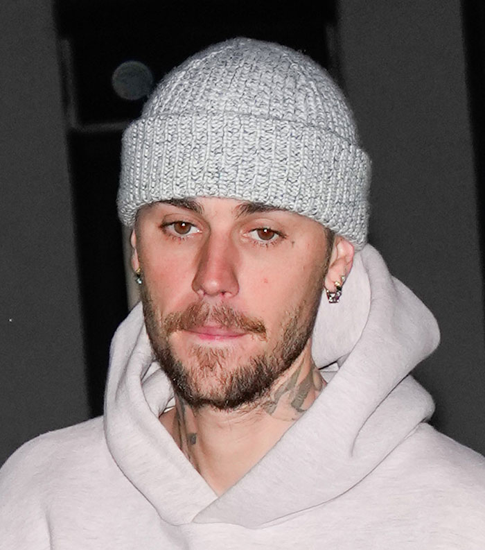 Close-up of a man wearing a gray knit beanie and hoodie, representing the most disliked celebrities of 2025.