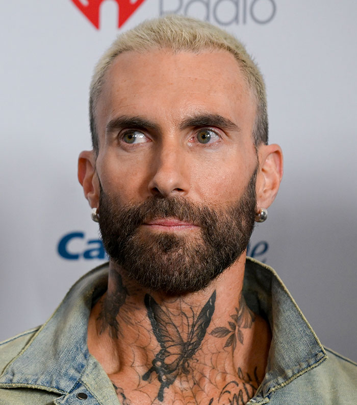 Close-up of a tattooed male celebrity with a blonde buzz cut and beard, representing most disliked celebrities of 2025.