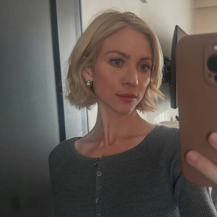 Britanny Snow taking a selfie indoors with short blonde hair, wearing earrings and a grey buttoned top, addressing plastic surgery rumors. Britanny Snow taking a selfie indoors with short blonde hair, wearing earrings and a grey buttoned top, addressing plastic surgery rumors.