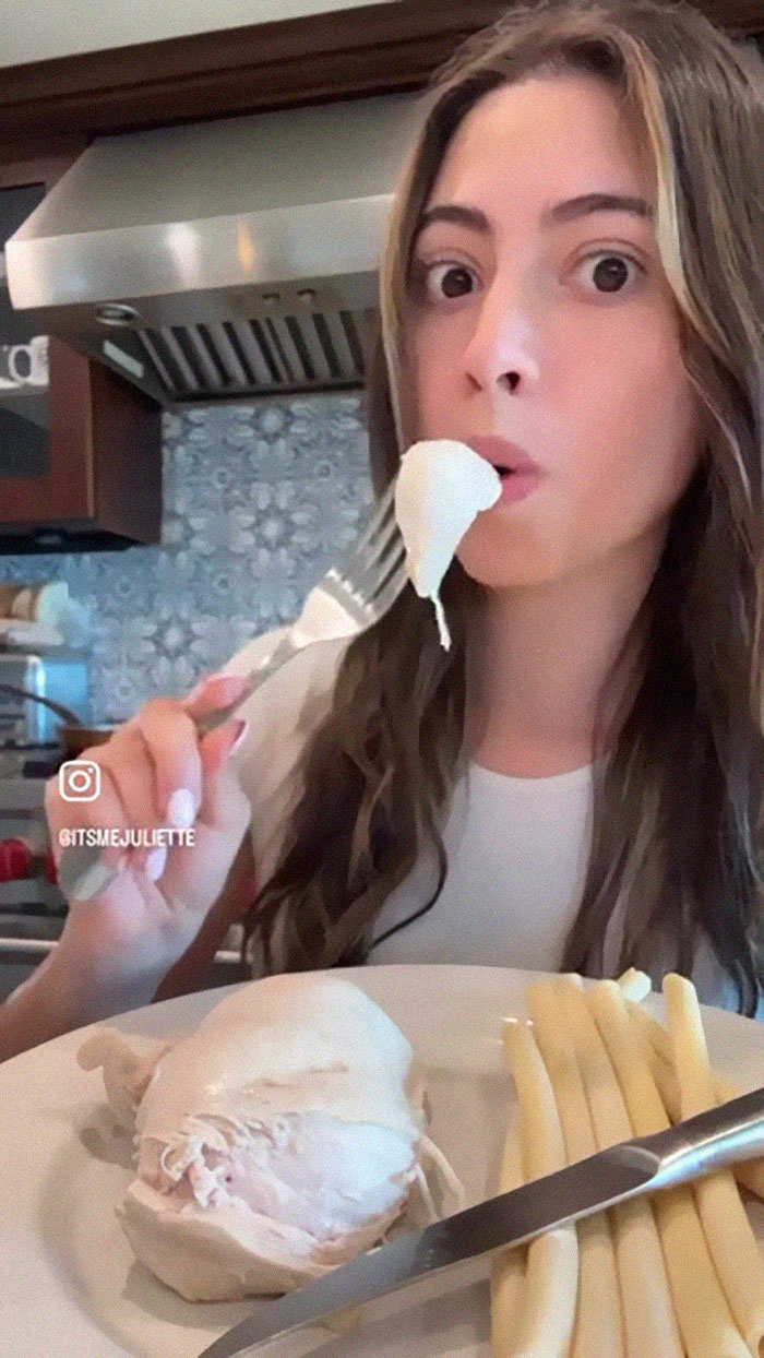 Woman eating food cooked in dishwasher in kitchen with chicken breast and white asparagus on plate Woman eating food cooked in dishwasher in kitchen with chicken breast and white asparagus on plate