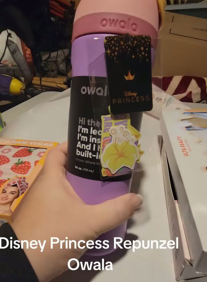 Hand holding a purple Disney Princess Repunzel Owala water bottle in a Christmas gift haul for daughter.