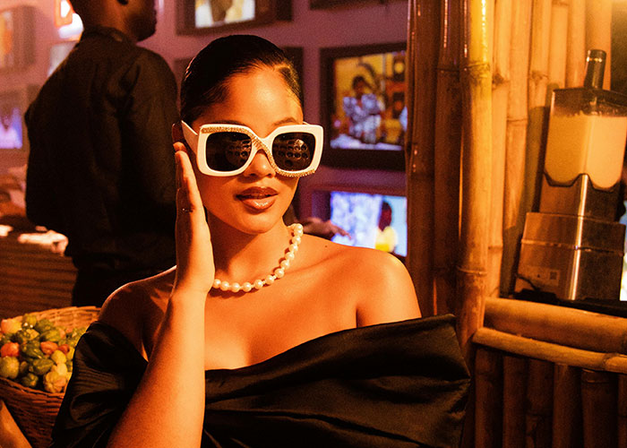 Woman in oversized sunglasses and pearl necklace in a luxury setting, illustrating rip-offs in luxury industries.