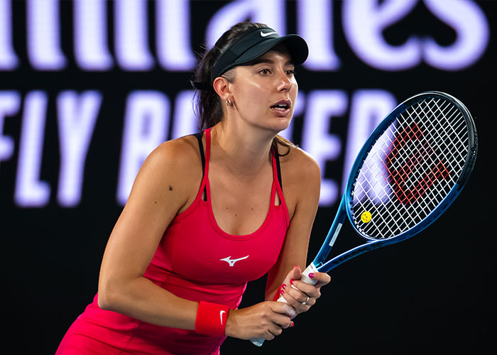 Female tennis player in red outfit preparing to return a serve during a professional match, highlighting tennis star career transition. Female tennis player in red outfit preparing to return a serve during a professional match, highlighting tennis star career transition.