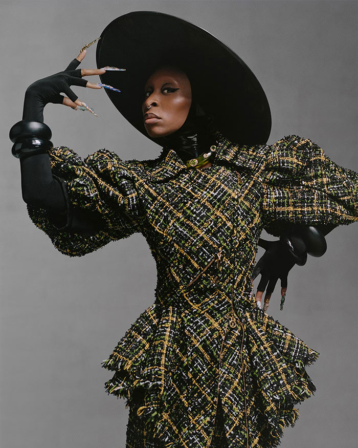 Cynthia Erivo posing in a black hat and textured dress with oddly large hands creating a dramatic, demon-like effect. Cynthia Erivo posing in a black hat and textured dress with oddly large hands creating a dramatic, demon-like effect.