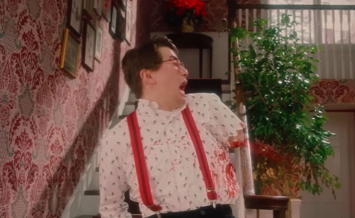 Man with glasses and red suspenders shocked and bleeding in SNL’s Home Alone parody with a bloody twist dividing fans. Man with glasses and red suspenders shocked and bleeding in SNL’s Home Alone parody with a bloody twist dividing fans.