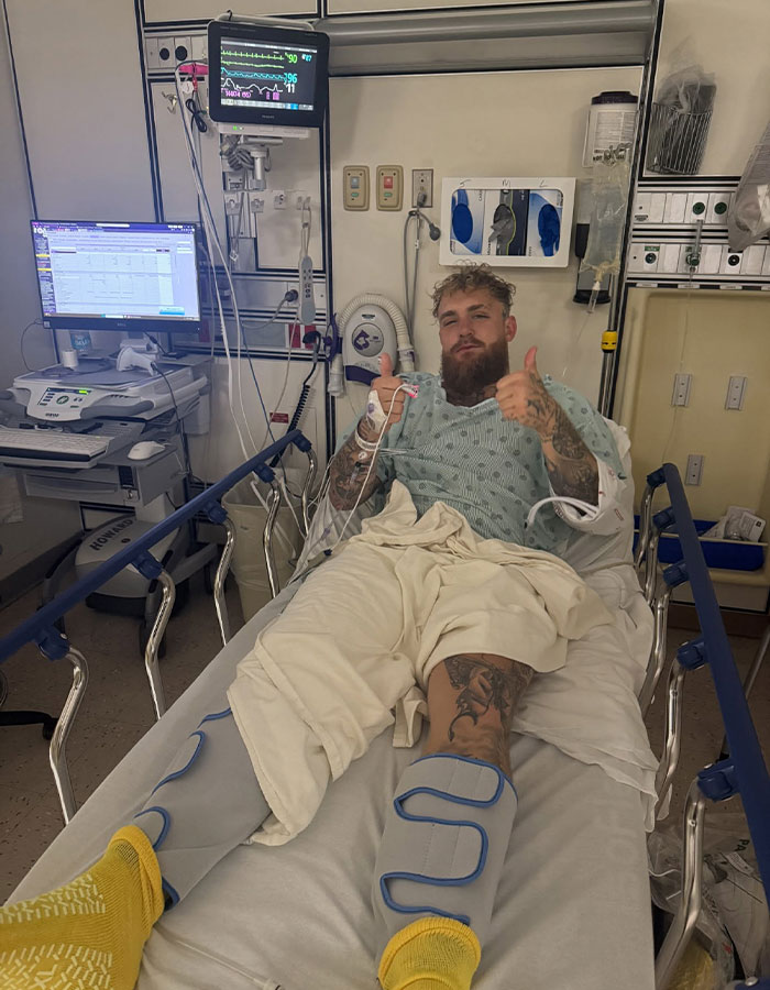 Man in hospital bed with leg braces giving thumbs up, highlighting Jake Paul's broken jaw trending on the internet. Man in hospital bed with leg braces giving thumbs up, highlighting Jake Paul's broken jaw trending on the internet.