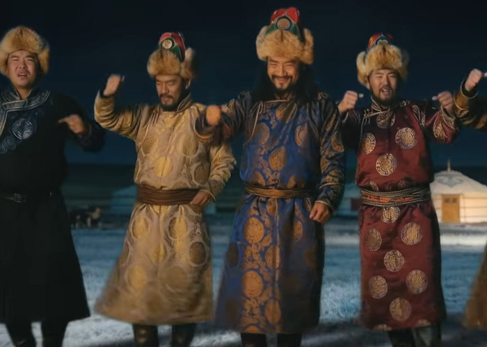 Four men in traditional Mongolian attire performing throat singing outdoors at night in a snowy landscape for viral Christmas anthem. Four men in traditional Mongolian attire performing throat singing outdoors at night in a snowy landscape for viral Christmas anthem.