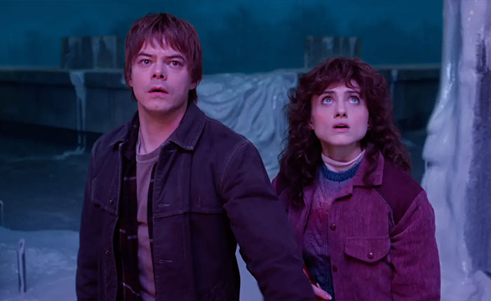 Two Stranger Things 5 characters in a dimly lit icy setting, looking shocked and concerned. Two Stranger Things 5 characters in a dimly lit icy setting, looking shocked and concerned.