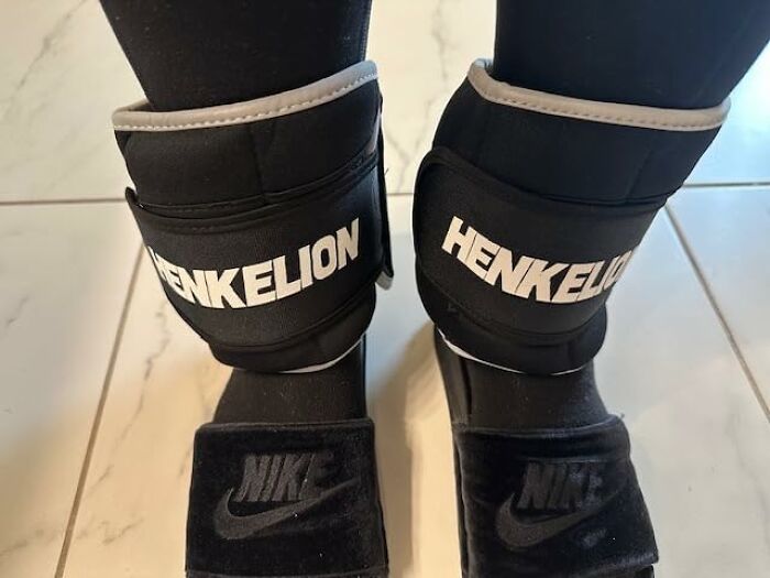 Ankle weights labeled Henkelion worn with Nike slides on tiled floor, demonstrating apartment friendly fitness gear.