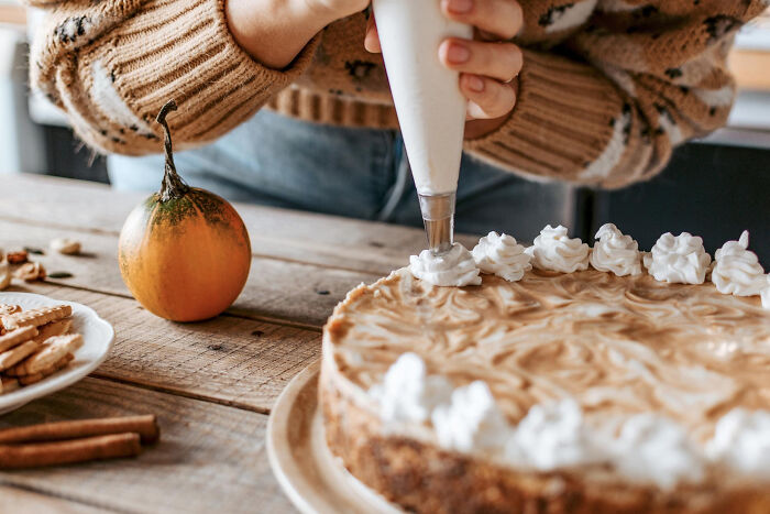 Person decorating a pumpkin pie with whipped cream, capturing an embarrassing moment people were blessed to see.
