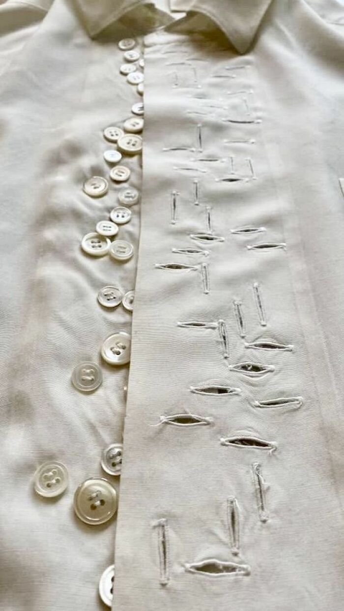 Close-up of a white shirt with numerous misplaced buttons and irregularly stitched buttonholes creating a trippy picture effect.