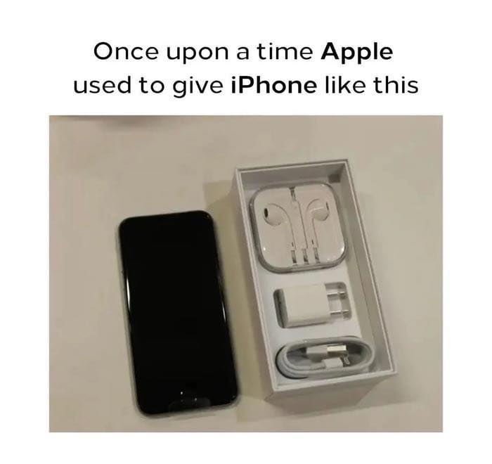 iPhone packaging with charger, earbuds, and phone displayed, highlighting sarcasm about Apple’s past accessory inclusion.