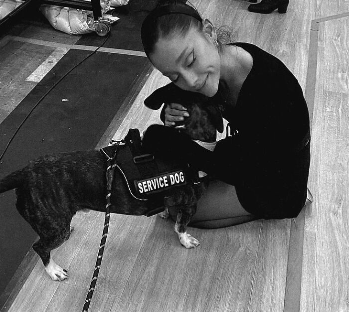 Ariana Grande sitting on the floor hugging a service dog, highlighting struggles and family support for mental health. Ariana Grande sitting on the floor hugging a service dog, highlighting struggles and family support for mental health.