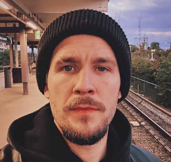 Close-up of Tylor Chase wearing a black beanie at a train station, highlighting his homelessness and urgent support request. Close-up of Tylor Chase wearing a black beanie at a train station, highlighting his homelessness and urgent support request.