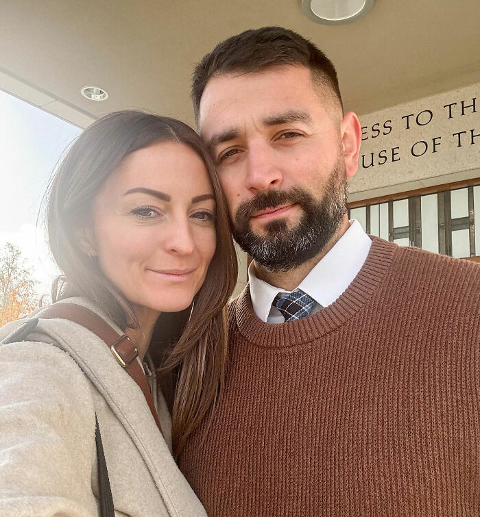 Couple posing closely outside a building, capturing a solemn moment related to influencer's daughter passing away.