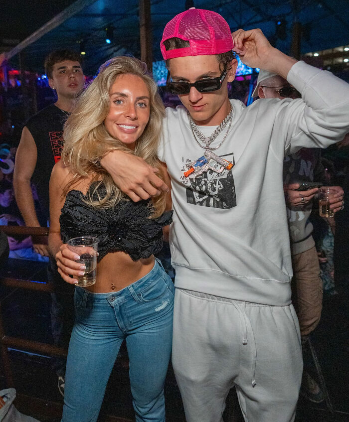 Two people posing in a party setting, with one wearing casual streetwear and the other holding a drink, Bonnie Blue context. Two people posing in a party setting, with one wearing casual streetwear and the other holding a drink, Bonnie Blue context.