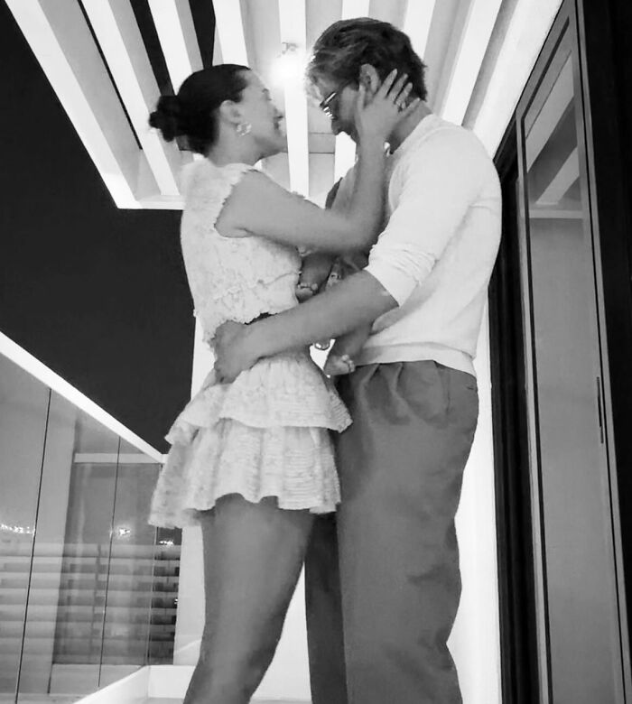 Couple embracing indoors in a modern setting, related to viral theory about Millie Bobby Brown's newborn daughter. Couple embracing indoors in a modern setting, related to viral theory about Millie Bobby Brown's newborn daughter.