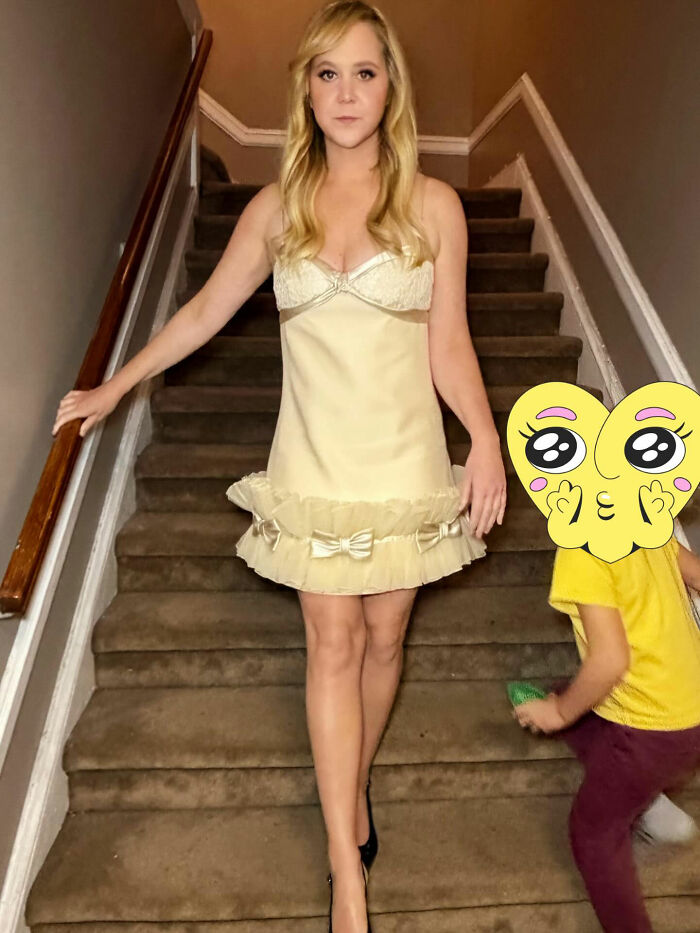 Amy Schumer showing off dramatic weight loss in a cream dress, standing on carpeted stairs with a child nearby. Amy Schumer showing off dramatic weight loss in a cream dress, standing on carpeted stairs with a child nearby.